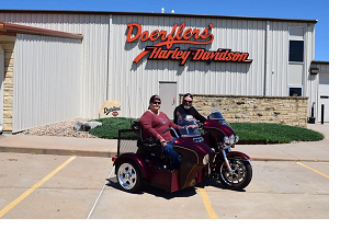 lou ann kibbe in a motorcycle side car in front of the harley shop