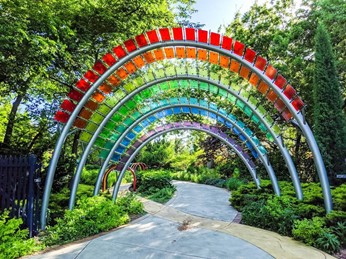 red, yellow, green, blue, and purple plastic arches supplementing the natural beauty on either side of a paved pathway