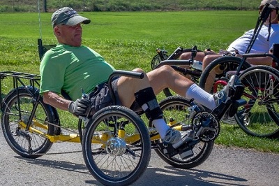 man with prosthetic leg in reclining pedal vehicle
